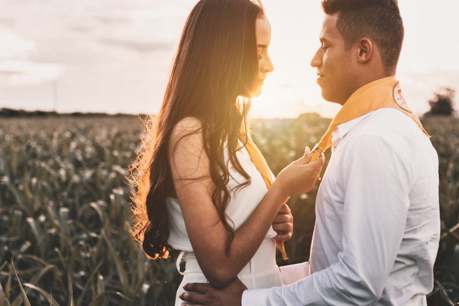CASAMENTO OU PRE WEDDING REALIZADO EM MARINGA PARANA COM UM CASAL JOVEM A CEU ABERTO NA IMAGEM A NOIVA ESTA AJUSTANDO O LENCO DOS DESBRAVADORES DO NOIVO COM MUITO CARINHO
