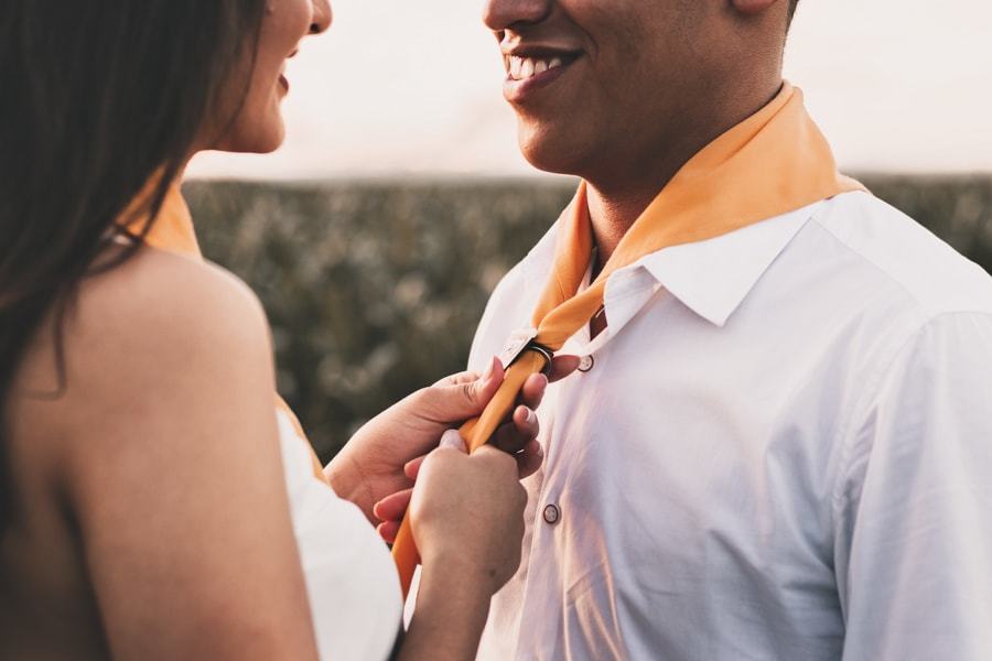CASAMENTO OU PRE WEDDING REALIZADO EM MARINGA PARANA COM UM CASAL JOVEM A CEU ABERTO NA IMAGEM A NOIVA ESTA AJUSTANDO O LENCO DOS DESBRAVADORES DO NOIVO COM MUITO CARINHO
