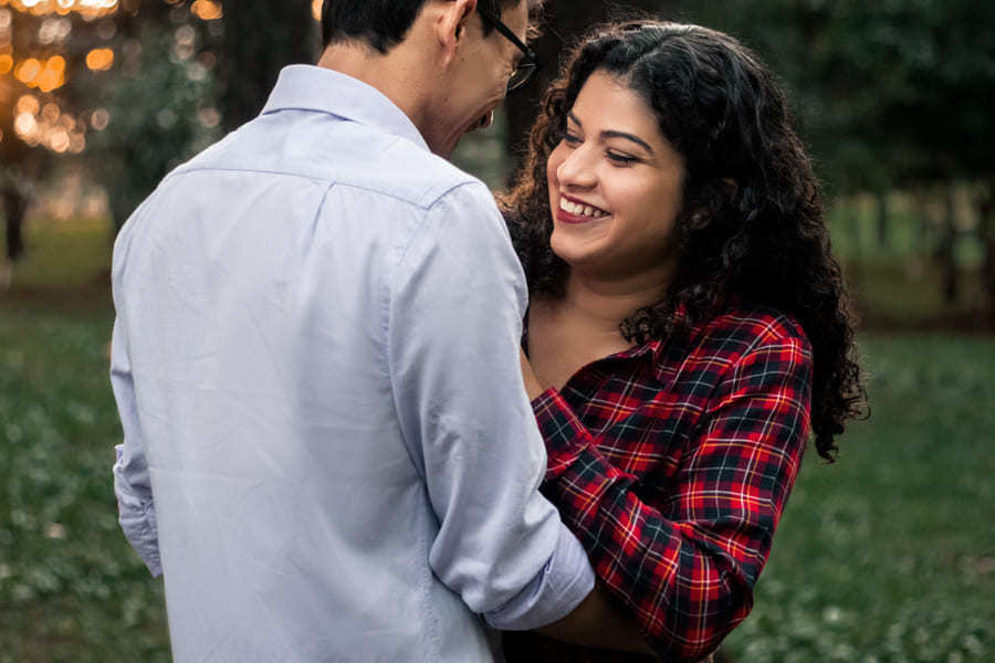 ENSAIO FOTOGRAFICO PRE CASAMENTO OU PRE WEDDING AO AR LIVRE EM BOSQUE DAS GREVILEAS GREVILIAS MARINGA NO PARANA NA IMAGEM O CASAL APARECE SORRINDO DE FRENTE UM PARA O OUTRO EM MEIO A VEGETACAO VERDE