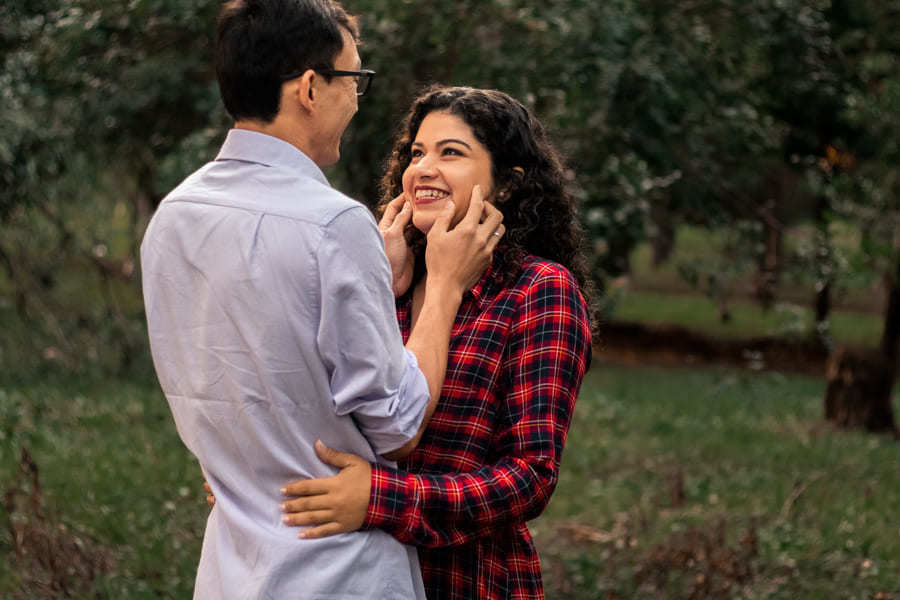 ENSAIO FOTOGRAFICO PRE CASAMENTO OU PRE WEDDING AO AR LIVRE EM BOSQUE DAS GREVILEAS GREVILIAS MARINGA NO PARANA NA IMAGEM O CASAL APARECE SORRINDO DE FRENTE UM PARA O OUTRO EM MEIO A VEGETACAO VERDE