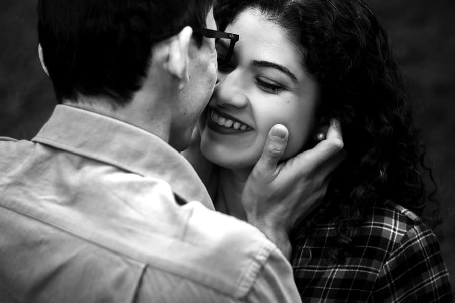 ENSAIO FOTOGRAFICO PRE CASAMENTO OU PRE WEDDING AO AR LIVRE EM BOSQUE DAS GREVILEAS GREVILIAS MARINGA NO PARANA NA IMAGEM EM PRETO E BRANCO O NOIVO APARECE ACARICIANDO O ROSTO DA NOIVA QUE SENTE O CARINHO DE OLHOS FECHADOS E SORRINDO COM AMOR