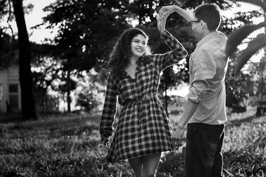 ENSAIO FOTOGRAFICO PRE CASAMENTO OU PRE WEDDING AO AR LIVRE EM BOSQUE DAS GREVILEAS GREVILIAS MARINGA NO PARANA NA IMAGEM O CASAL ESTA DANCANDO COM A NOIVA OLHANDO COM MUITO CARINHO PARA O NOIVO QUE A SEGURA FOTO EM PRETO E BRANCO