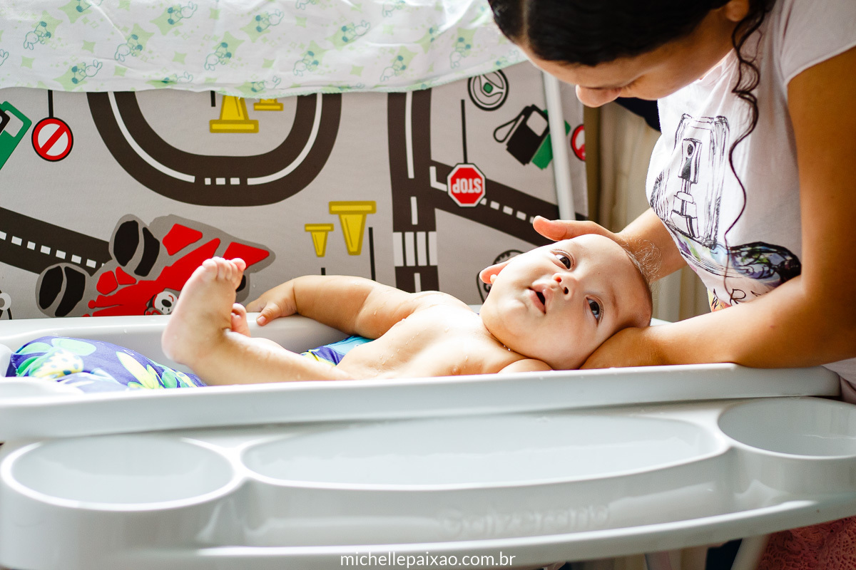 bebê na banheira branca com suporte mãe dá banho no bebê ensaio rotina do bebê rio de janeiro