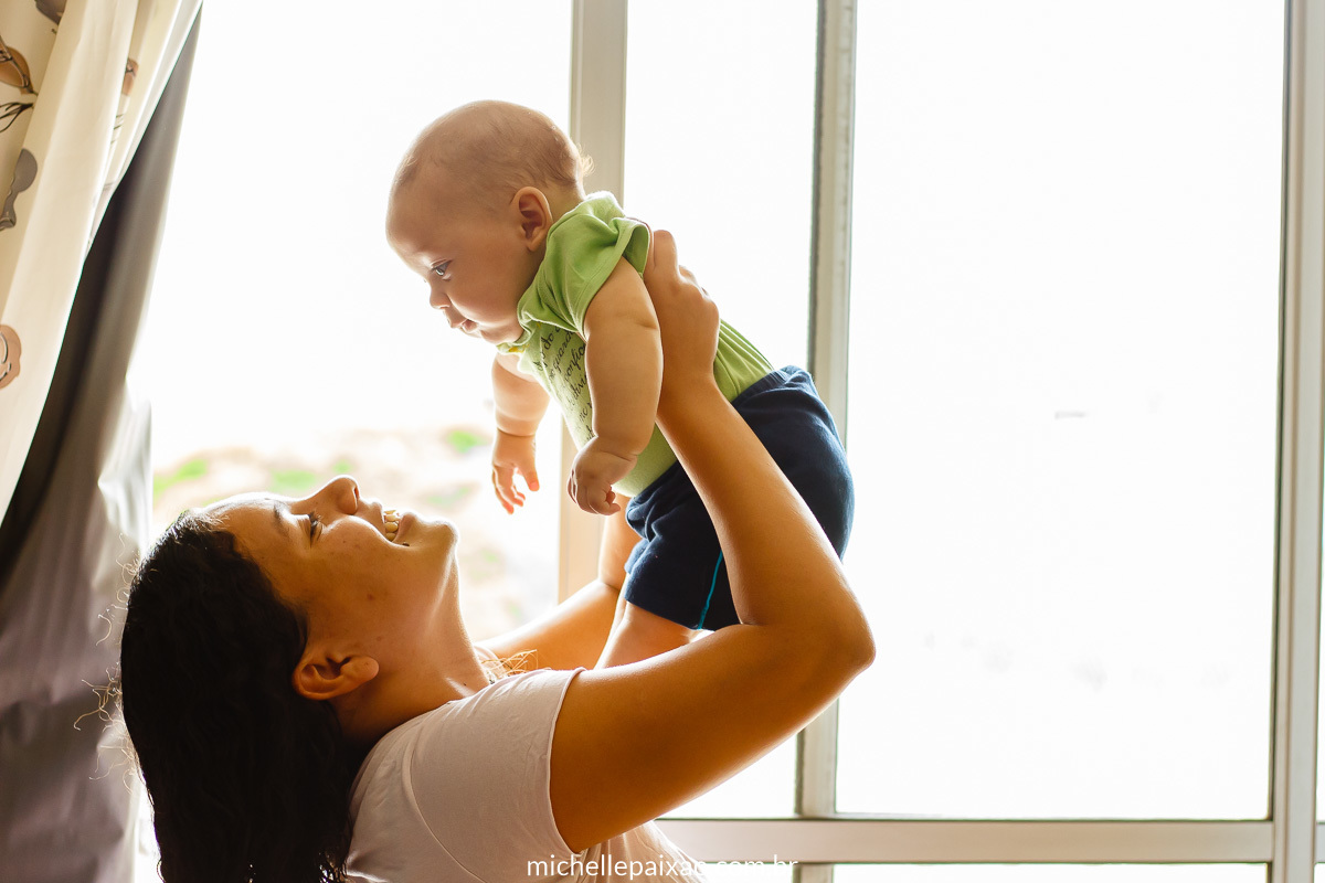 mãe segurando bebê no alto fotografia lifestyle de família rj