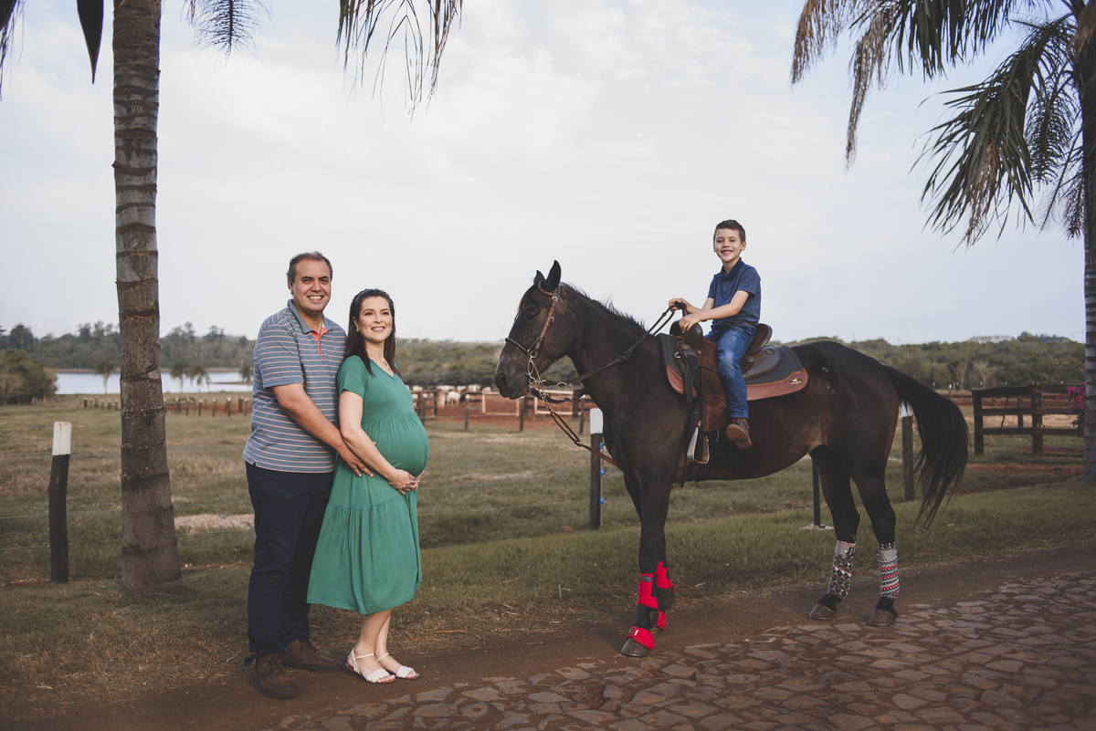 Foto de casal gestante com cavalo e filho na fazenda 