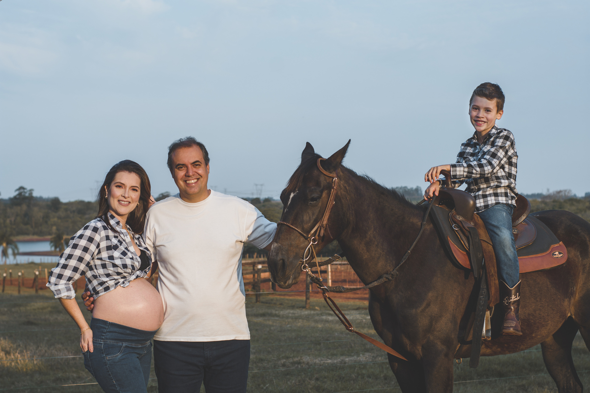 Foto de casal gestante com cavalo e filho na fazenda 