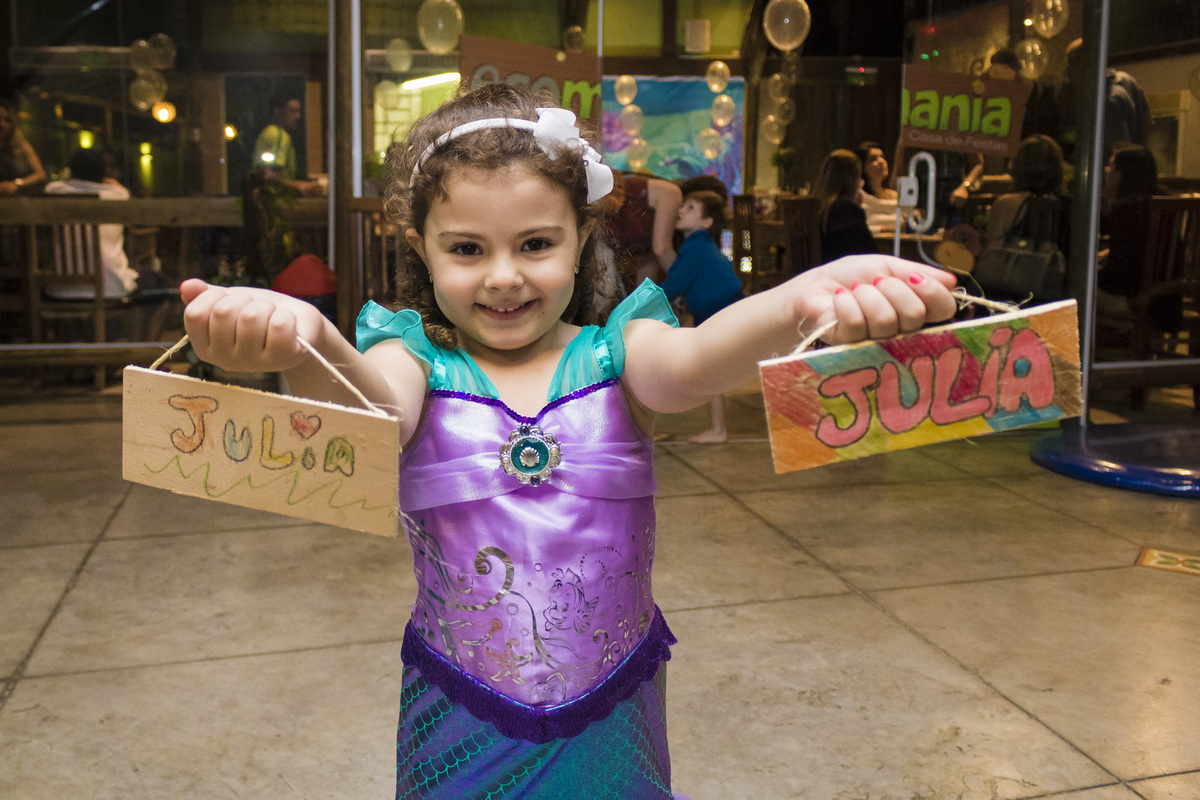 A aniversariante com fantasia de pequena sereia brincando em sua festa de aniversário