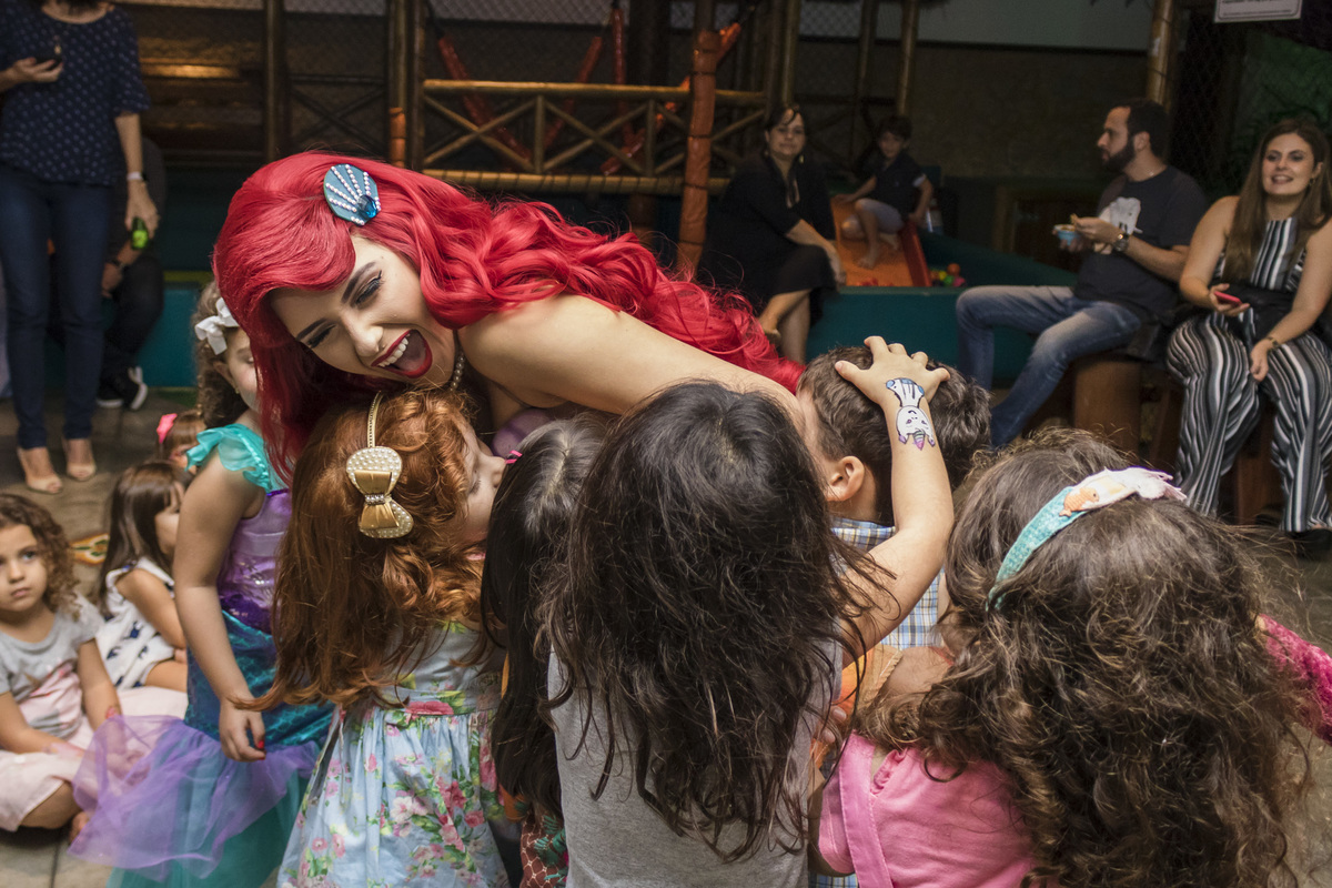 A pequena sereia, Ariel, sendo abraçada por todas as crianças na festa de aniversário