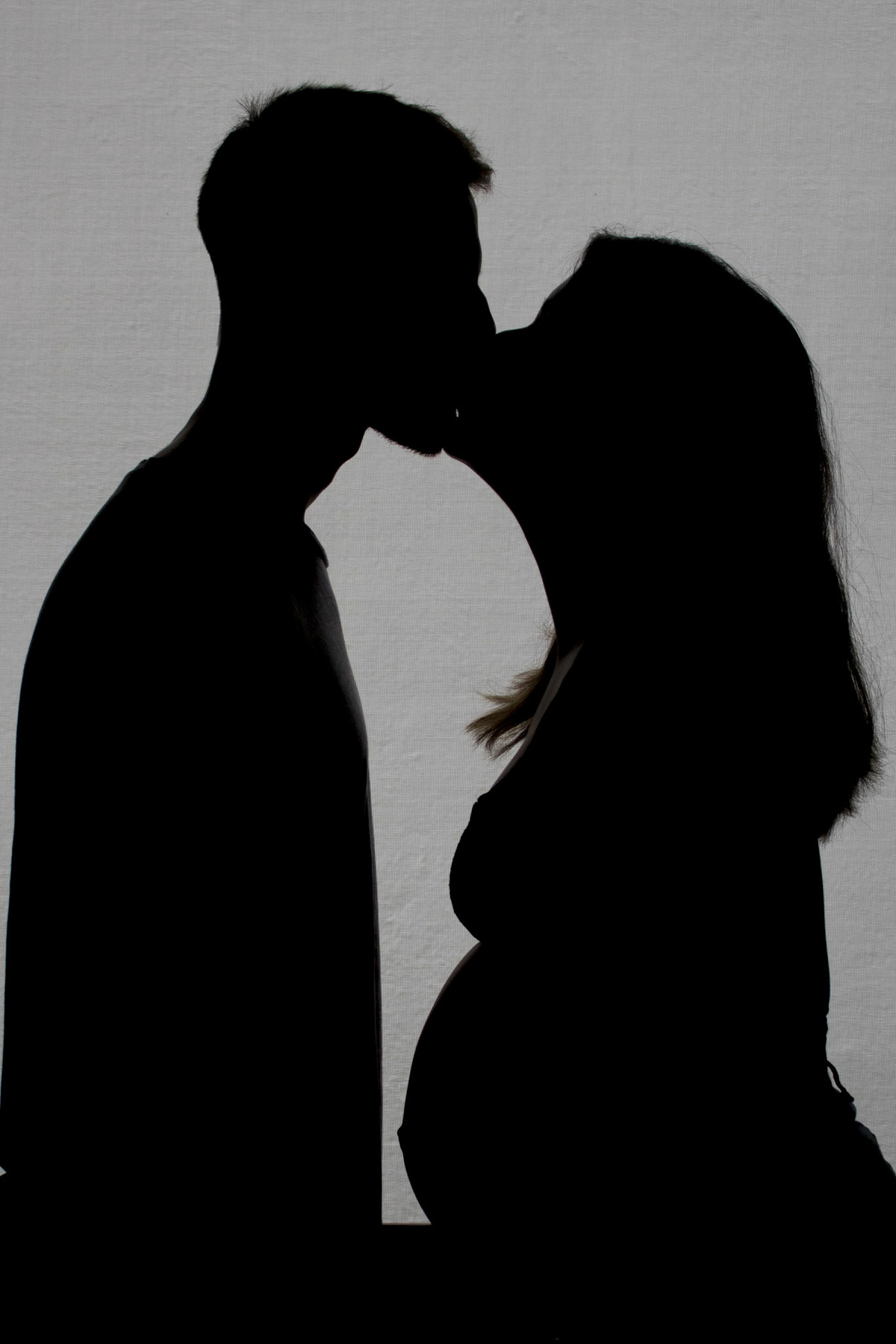 silueta da gestante e do pai se beijando