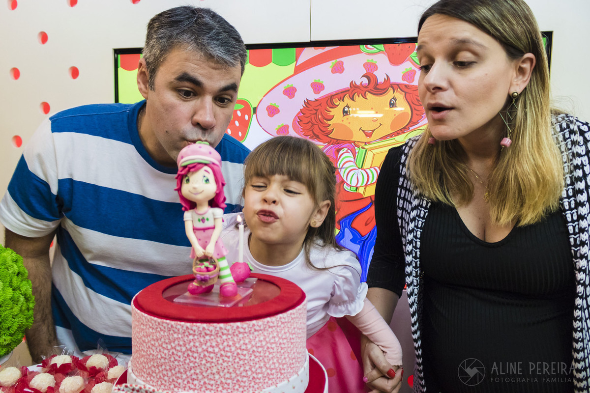 apagando as velas do bolo com tema moranguinho