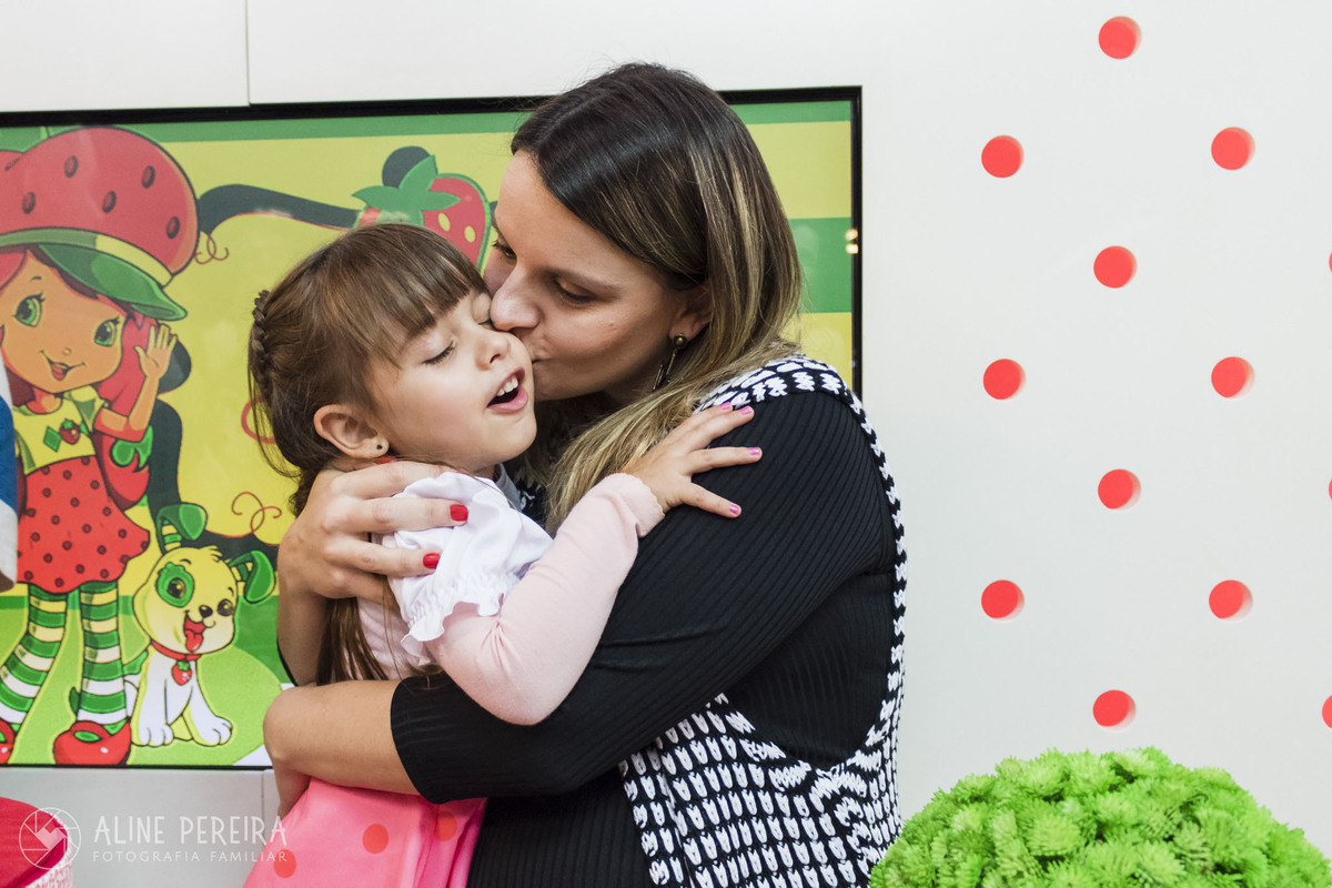 menina ganhando um beijo da mamãe na mesa do bolo moranguinho