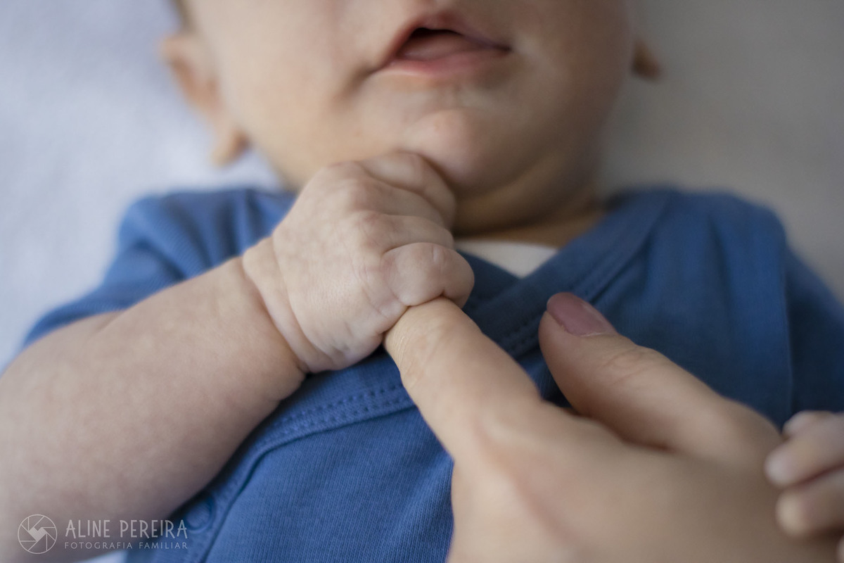 bebê segurando o dedo da mãe