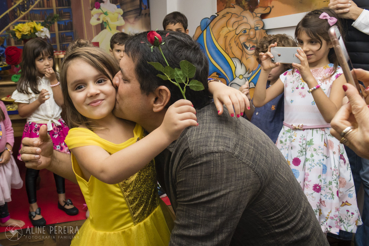 menina com vestido de Bela recebendo um beijo do pai