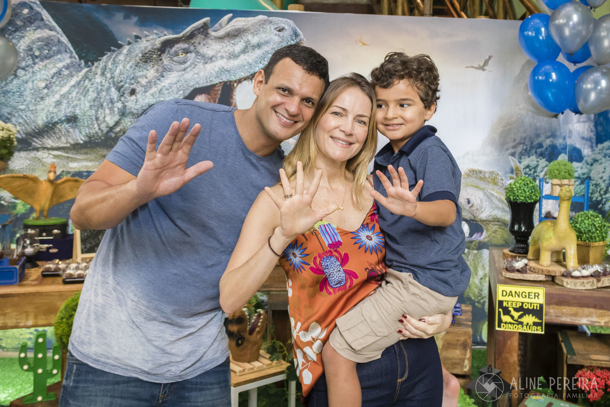 Familia em frente a Mesa do bolo decorada com o tema Dinossauros na casa de festas Ecomania