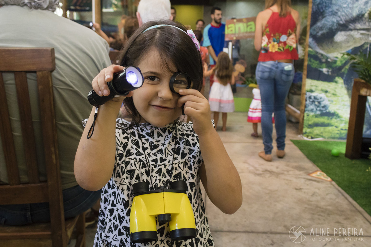 Menina brincando com binóculo, lanterna e lupa na festa de aniversário na casa de festas Ecomania