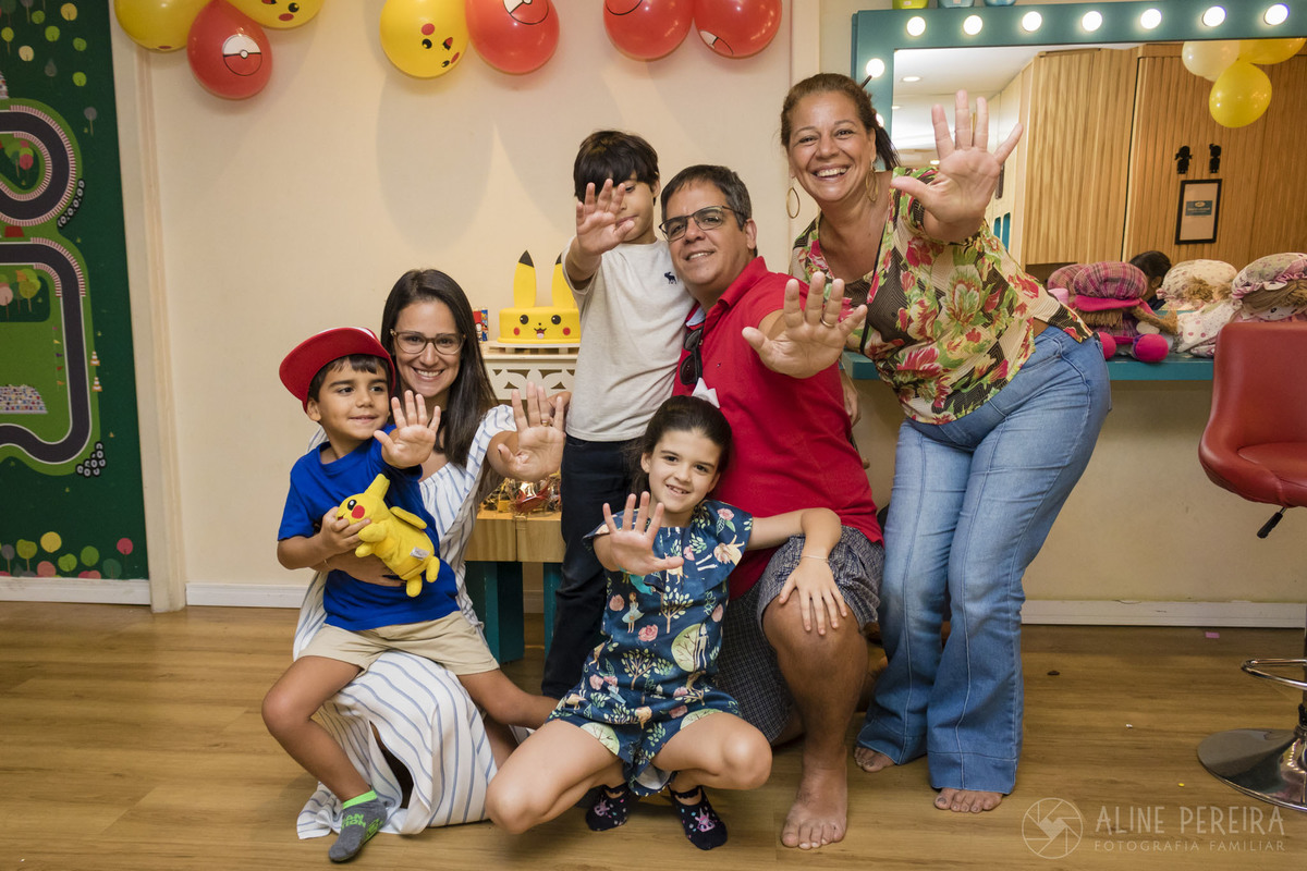Família em frente a mesa do bolo com o tema Pokemon na casa de festas Up Kids