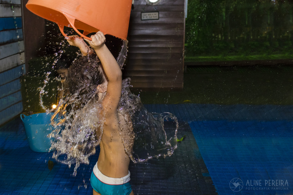 Menino jogando um balde cheio de água sobre si mesmo na área molhada da casa de festas Goiabeira Coisa e Tal
