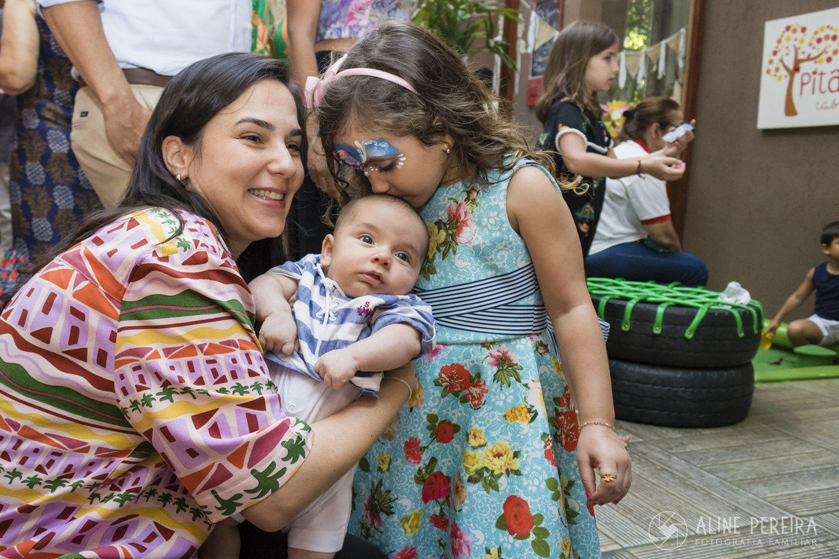 aniversariante beijando a cabeça do irmãozinho bebê