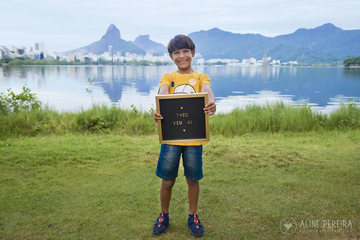 menino em frente a Lagoa Rodrigo de Freitas com a placa dizendo que o irmão vem ai