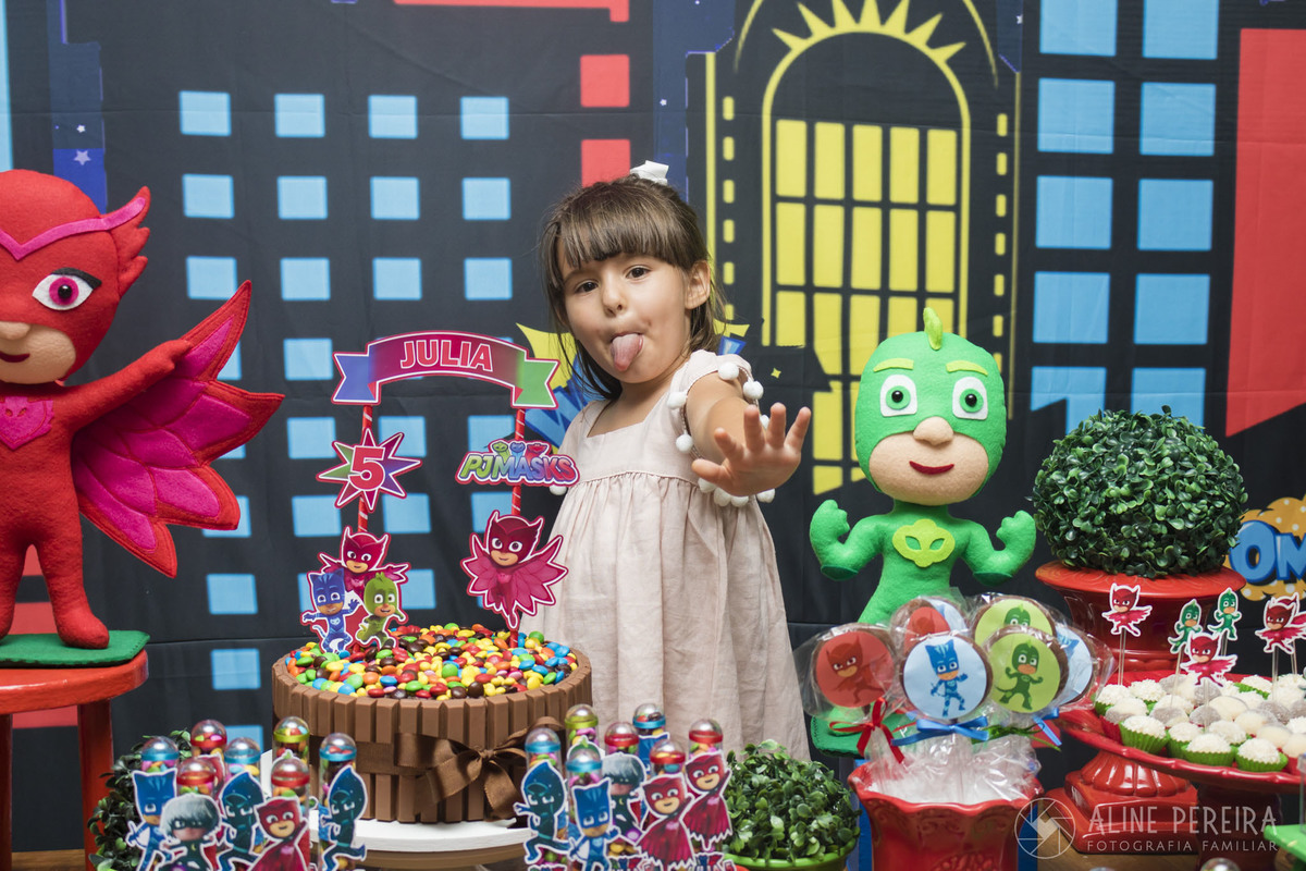 aniversariante na mesa do bolo decorada com o tema PJ Masks