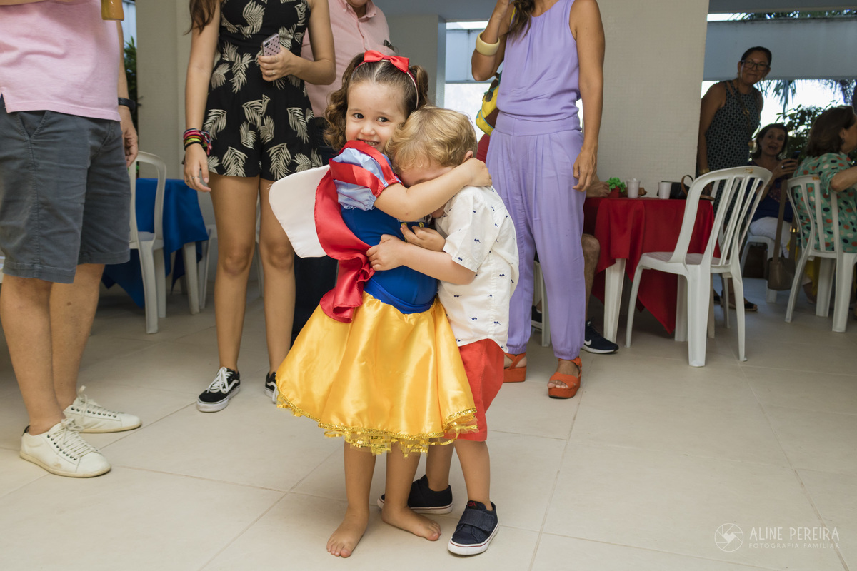 menina vestida de branca de neve dá um abraço apertado no amigo na sua festa de aniversário