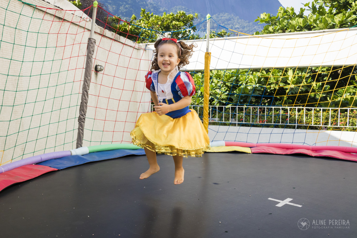 menina vestida de branca de neve brincando no pula-pula em sua festa de aniversário