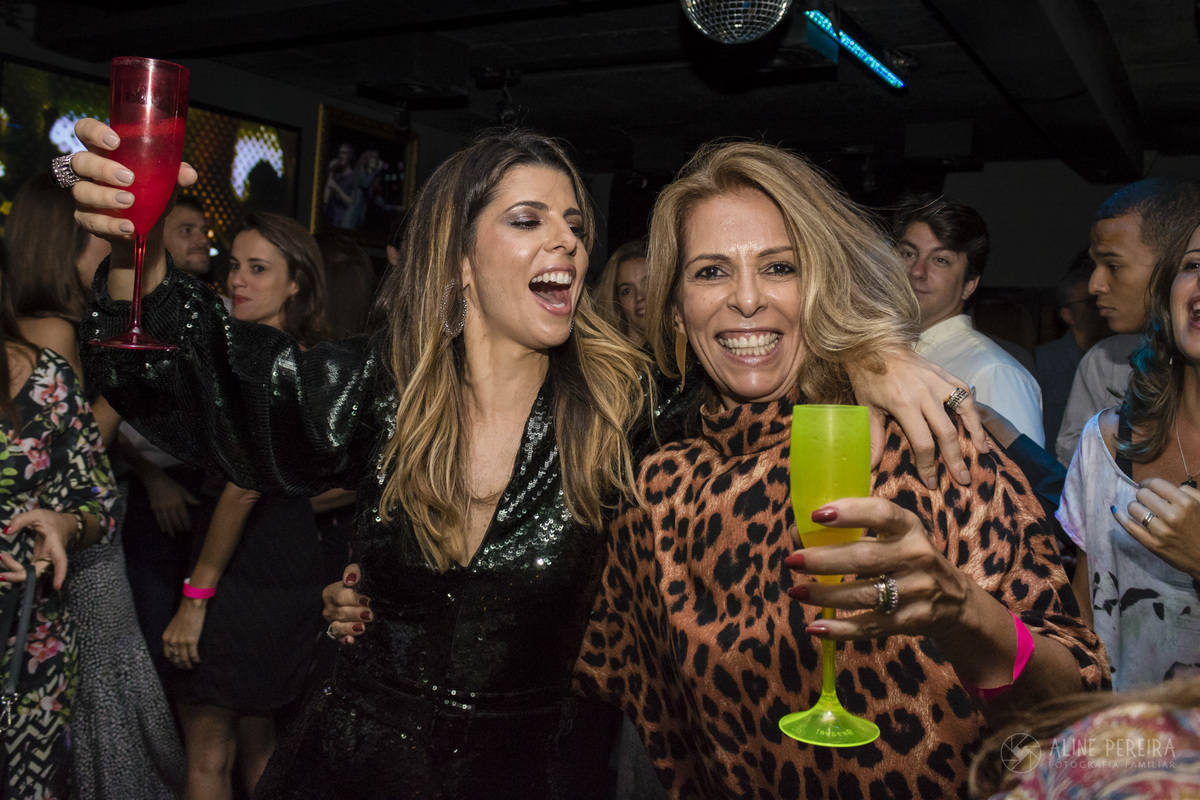 Mulheres dançando segurando taças na festa de aniversário de 40 anos na Flashback em Ipanema