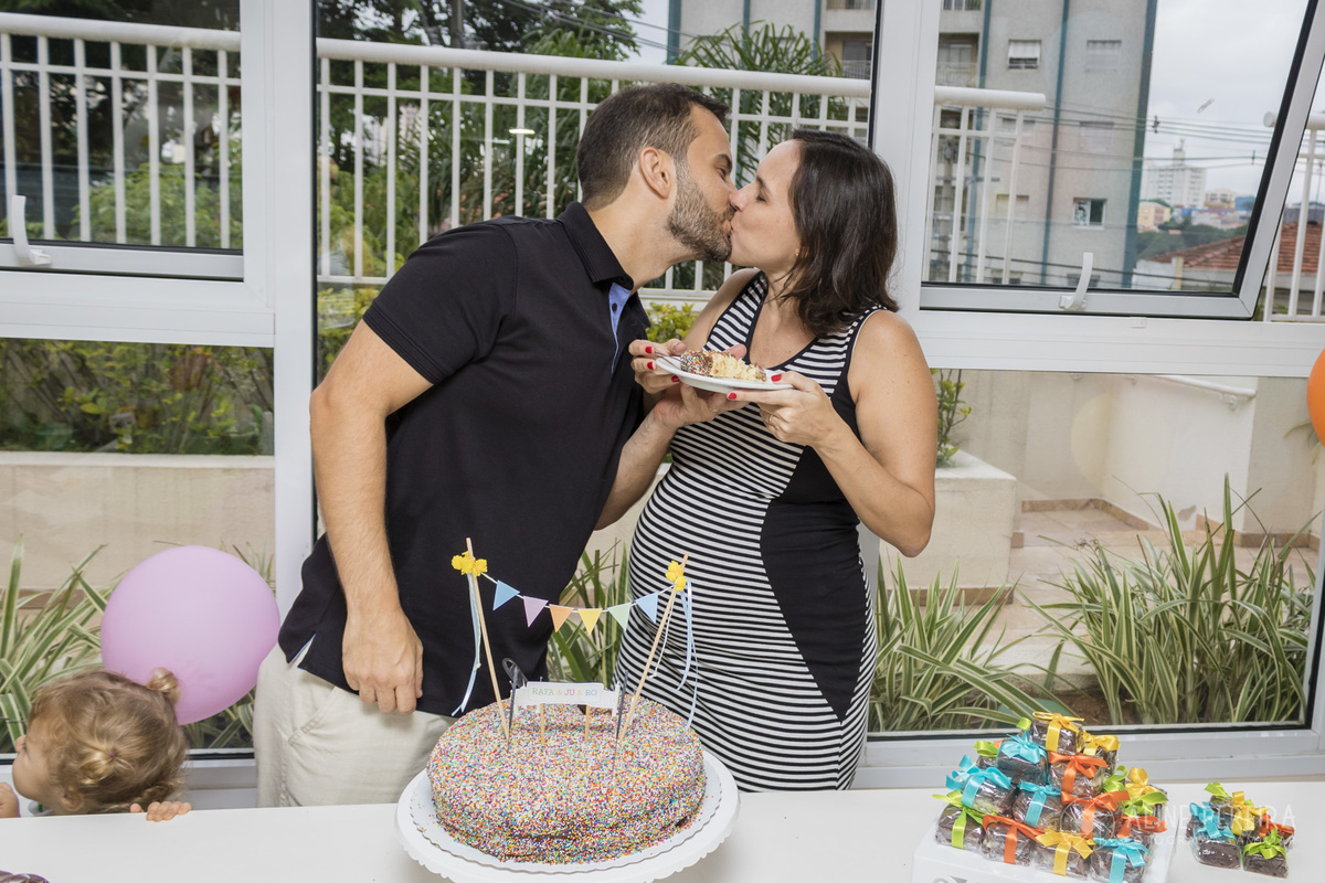 casal se beijando na mesa do bolo decorada do chá de bebê