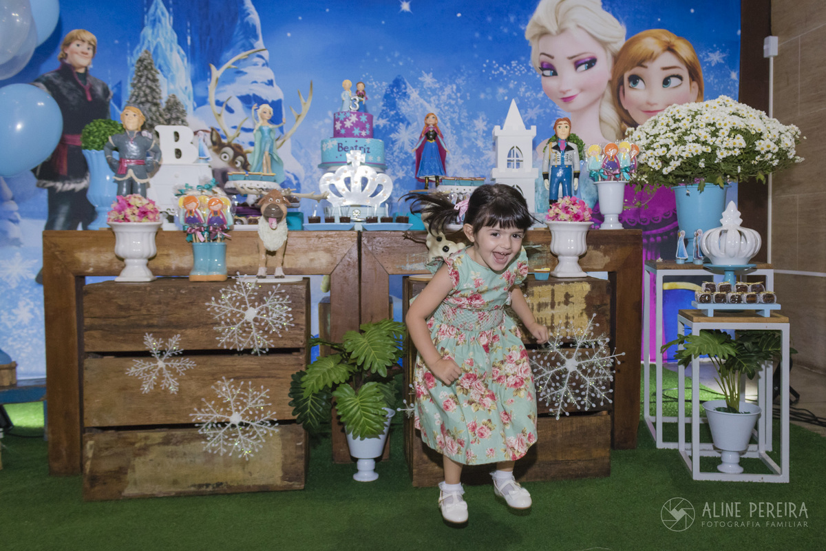 menina pulando em frente a mesa do bolo decorada com o tema Frozen na casa de festas Ecomania em Botafogo