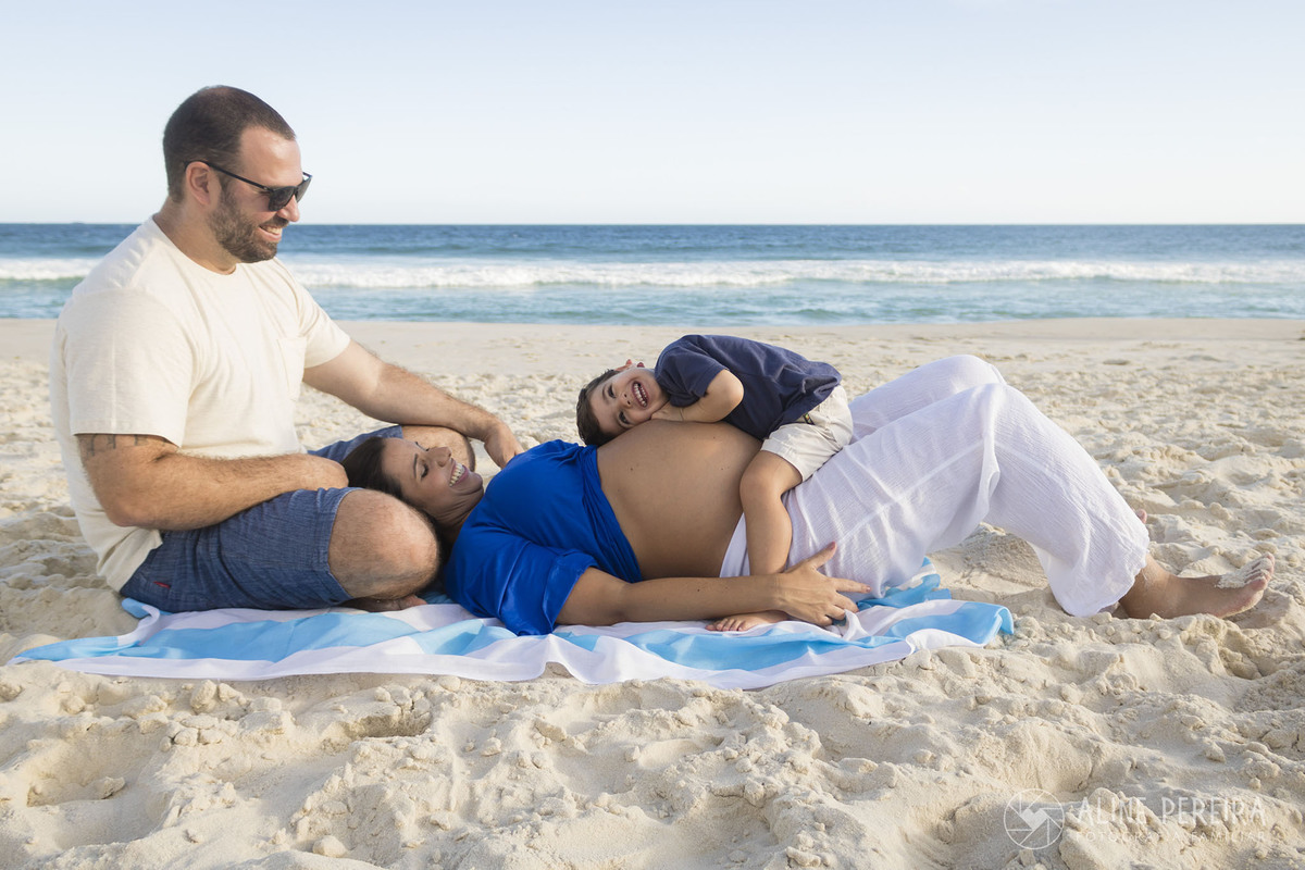 Familia de pai, mãe e filho brincando na areia da praia da barra da tijuca