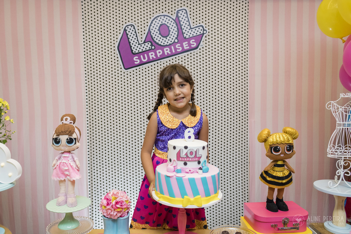 Menina com fantasia de LOL na mesa do bolo decorada com o tema LOL
