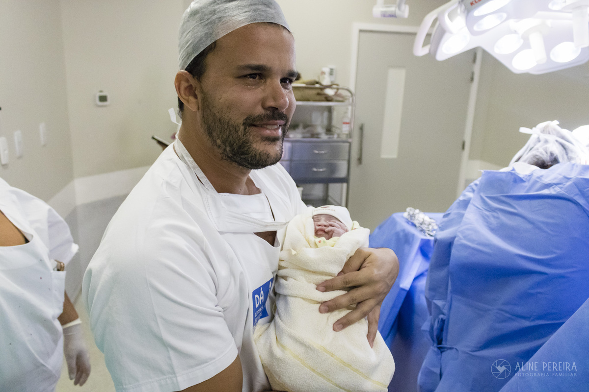 pai emocionado ao segurar a filha pela primeira vez na sala de parto