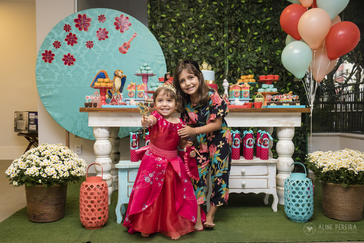 aniversariante em frente a mesa do bolo decorada com o tema elena de avalor