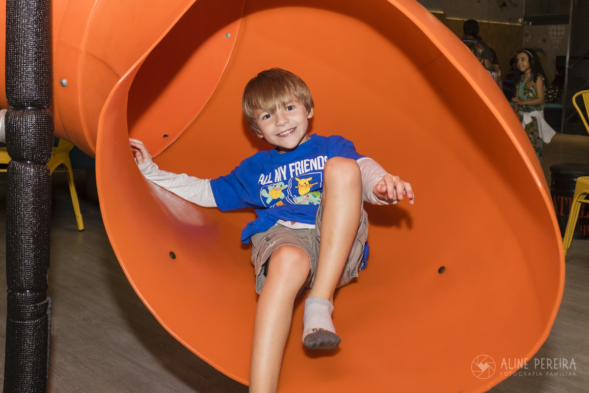 Criança descendo o escorrega laranja da casa de festas