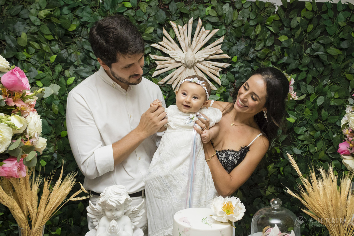 familia brincando com a filha na mesa decorada para o batizado