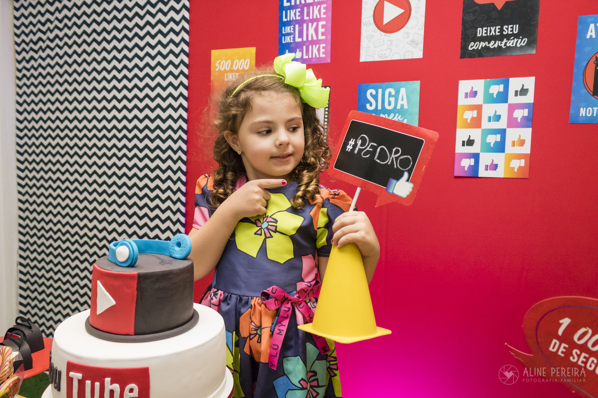 menina na mesa do bolo decorada com o tema youtuber