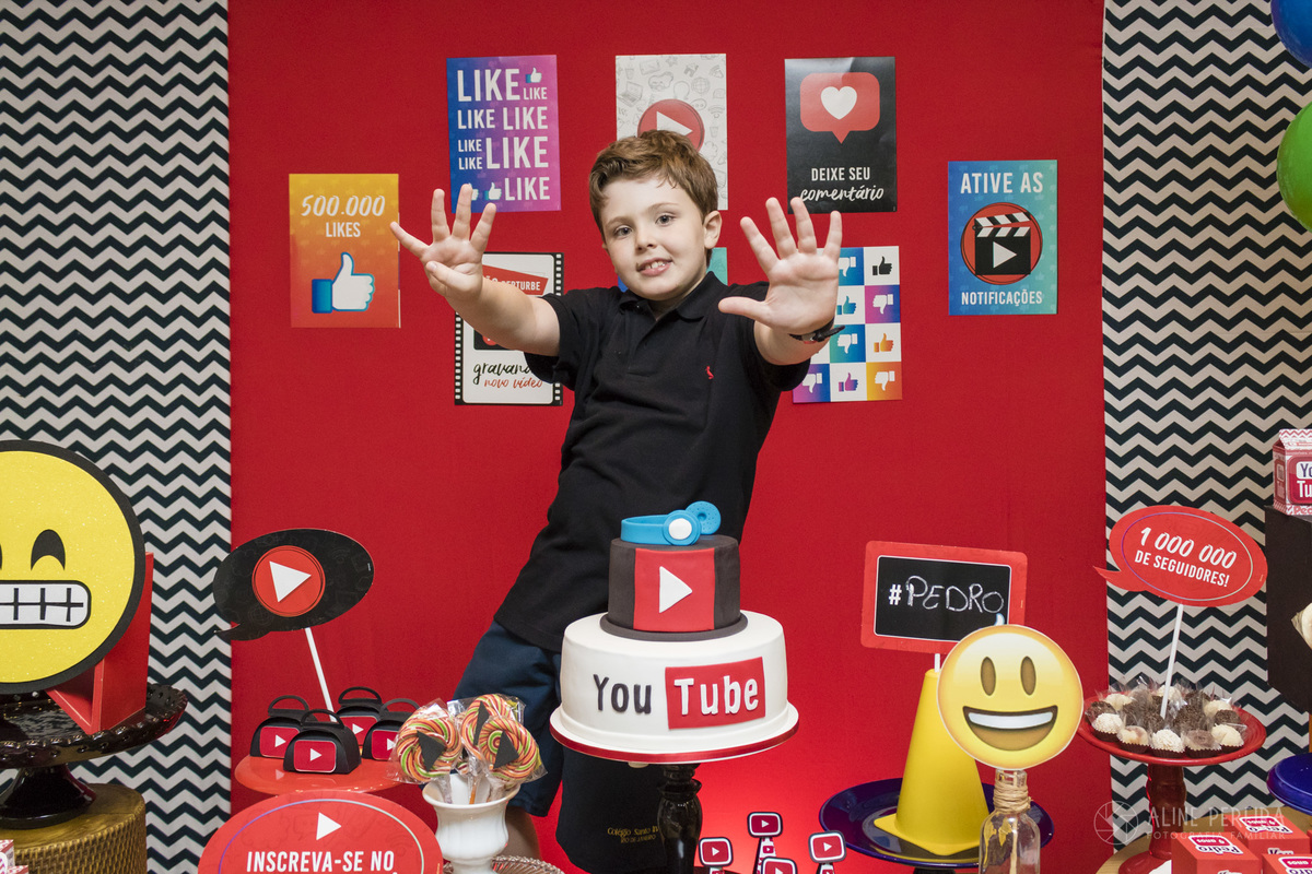 menino na mesa do bolo decorada com o tema youtuber