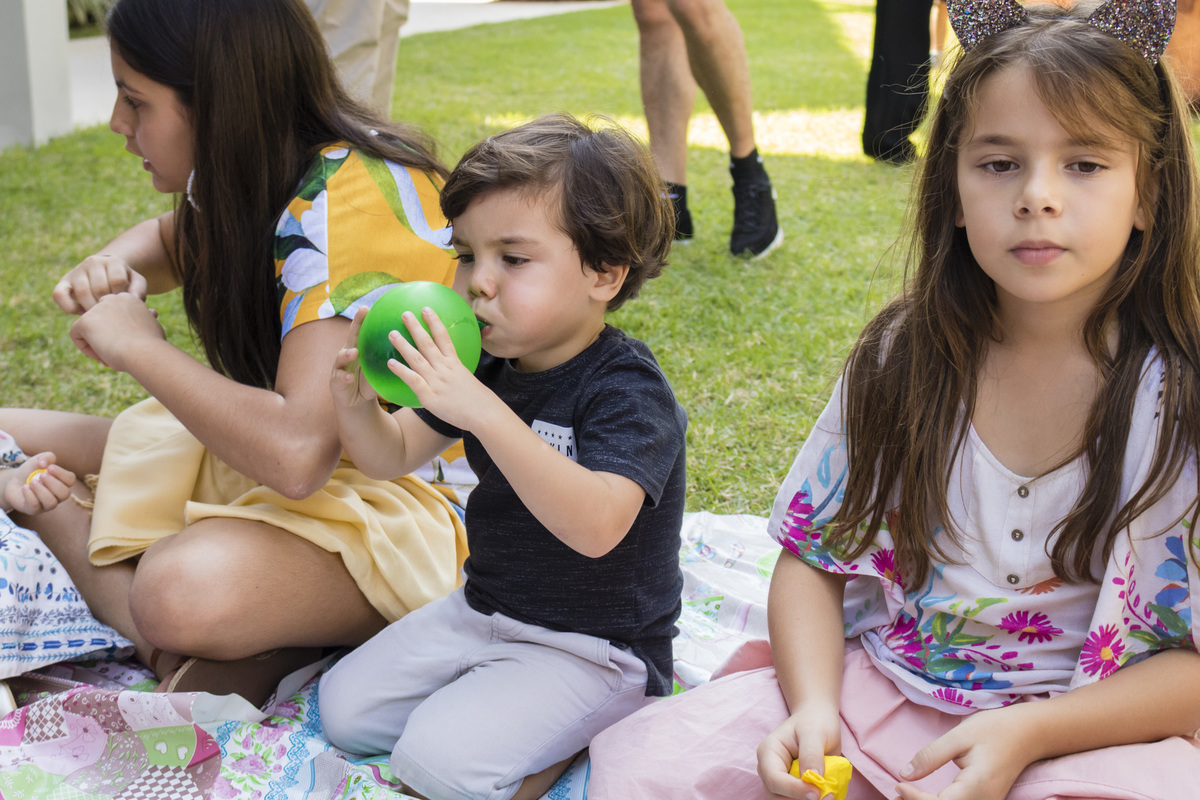 menino enchendo uma bexiga na festa de aniversário ao ar livre