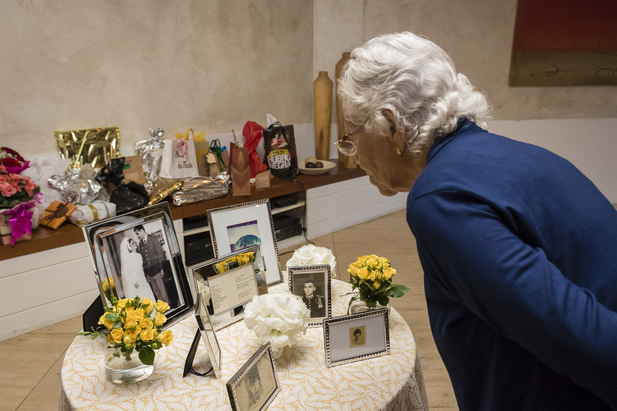 mulher idosa olhando as fotografias expostas na festa de bodas de ouro de um casal