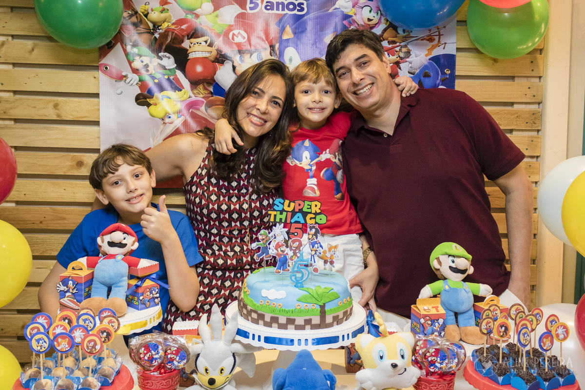 Família na mesa do bolo decorada com o tema Sonic e Mario Bros