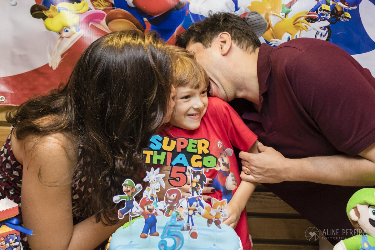 família beijando o menino na sua festa de aniversário com o tema Sonic e Mario Bros