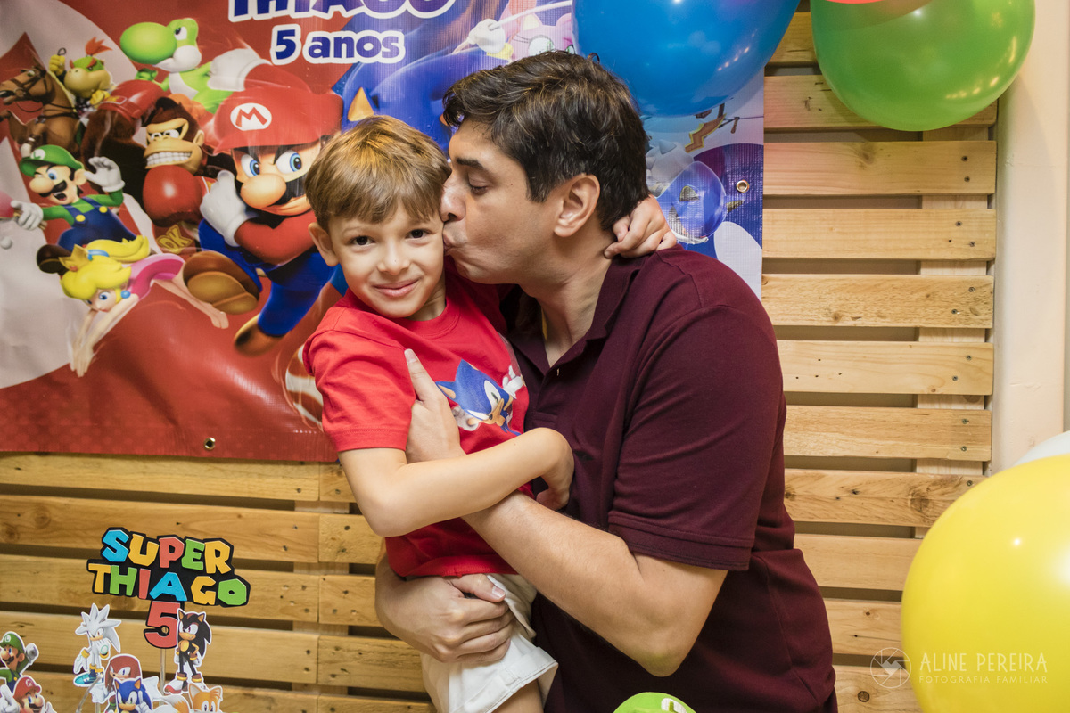 Pai beijando o filho na mesa do bolo decorada com o tema Sonic