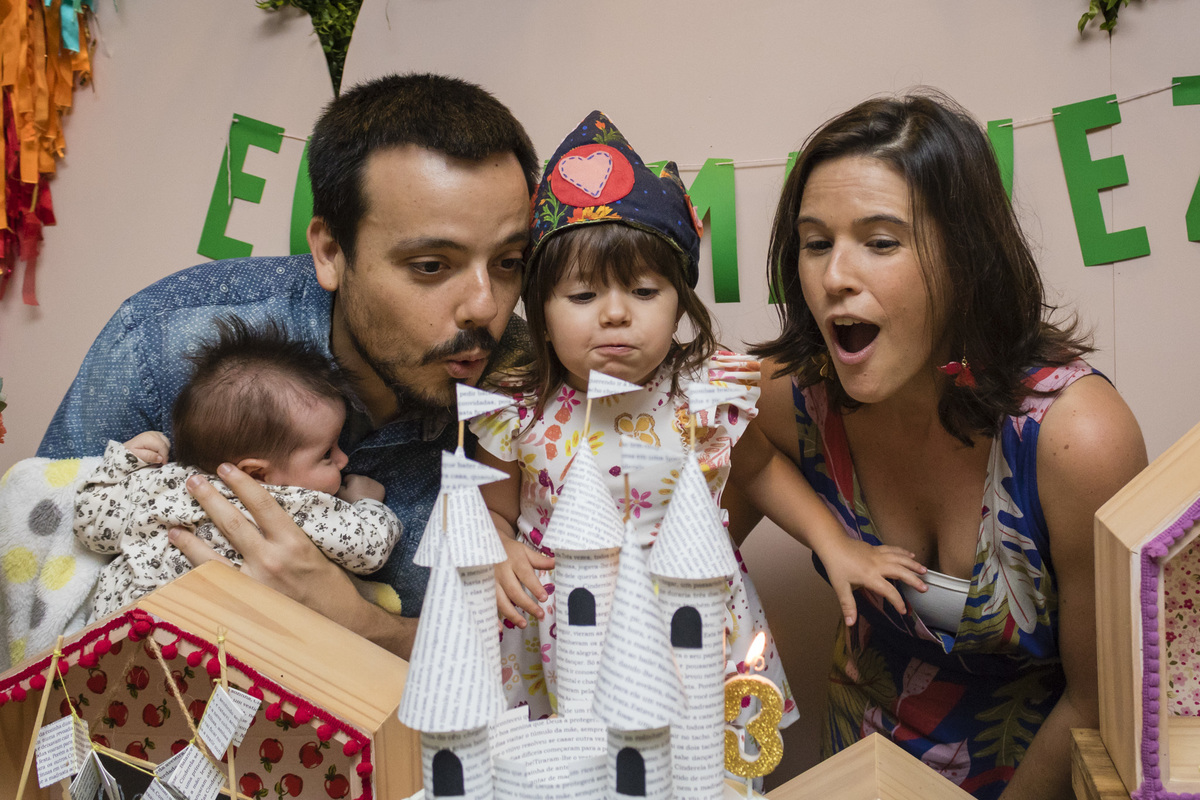 família apagando a vela do bolo de aniversário com o tema contos infantis