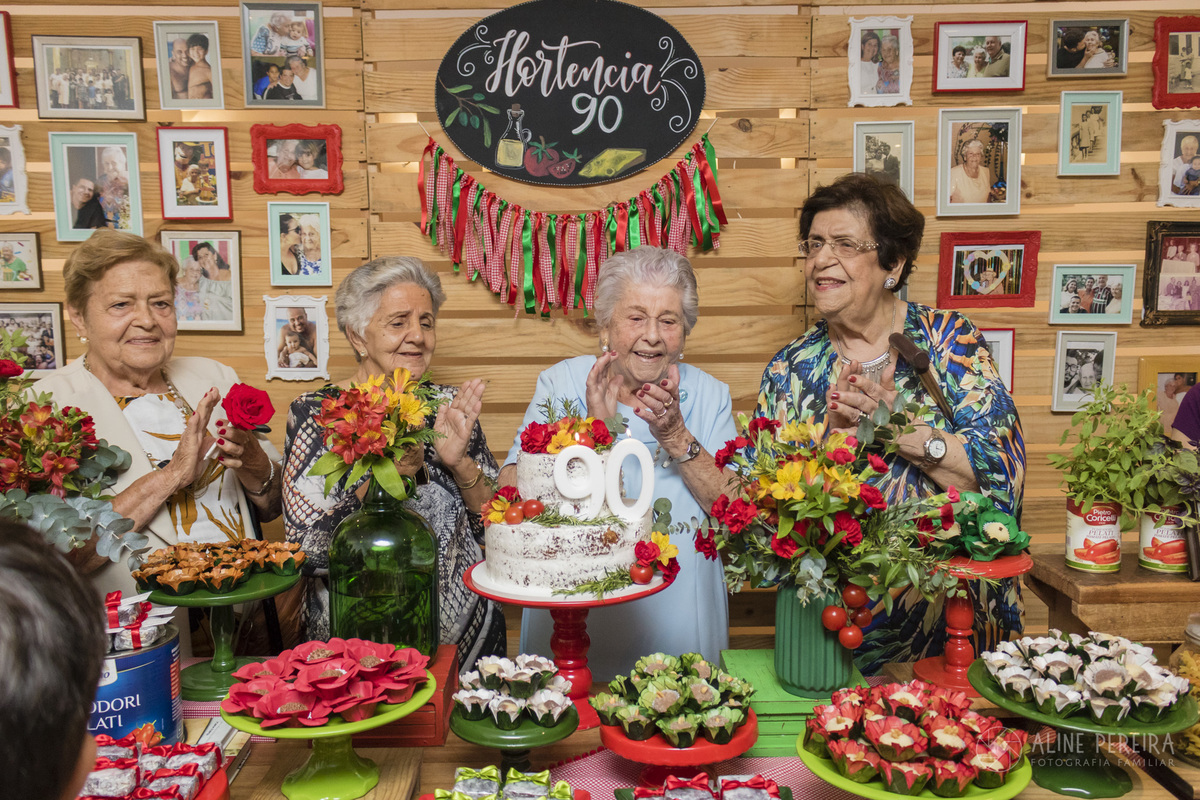 senhora idosa na mesa do bolo com as amigas cantando parabéns na mesa do bolo com tema Itália