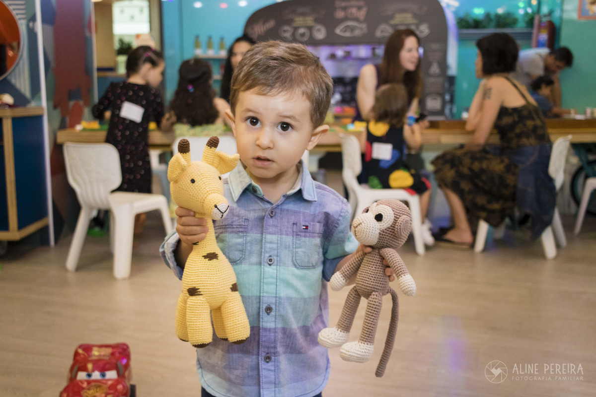 menino pequeno segurando amigurumi de girafa e de macaco