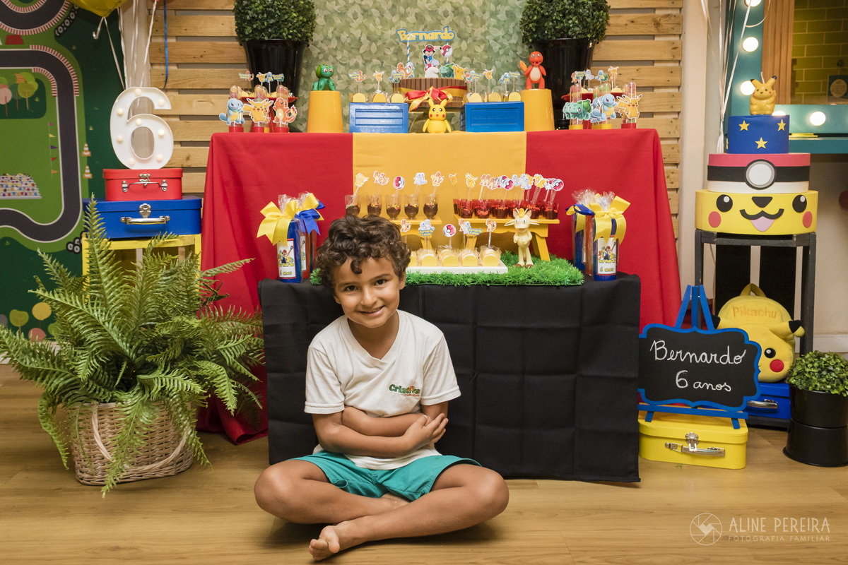 aniversariante na frente da mesa do bolo com o tema pokemon na Up Kids no shopping da gavea