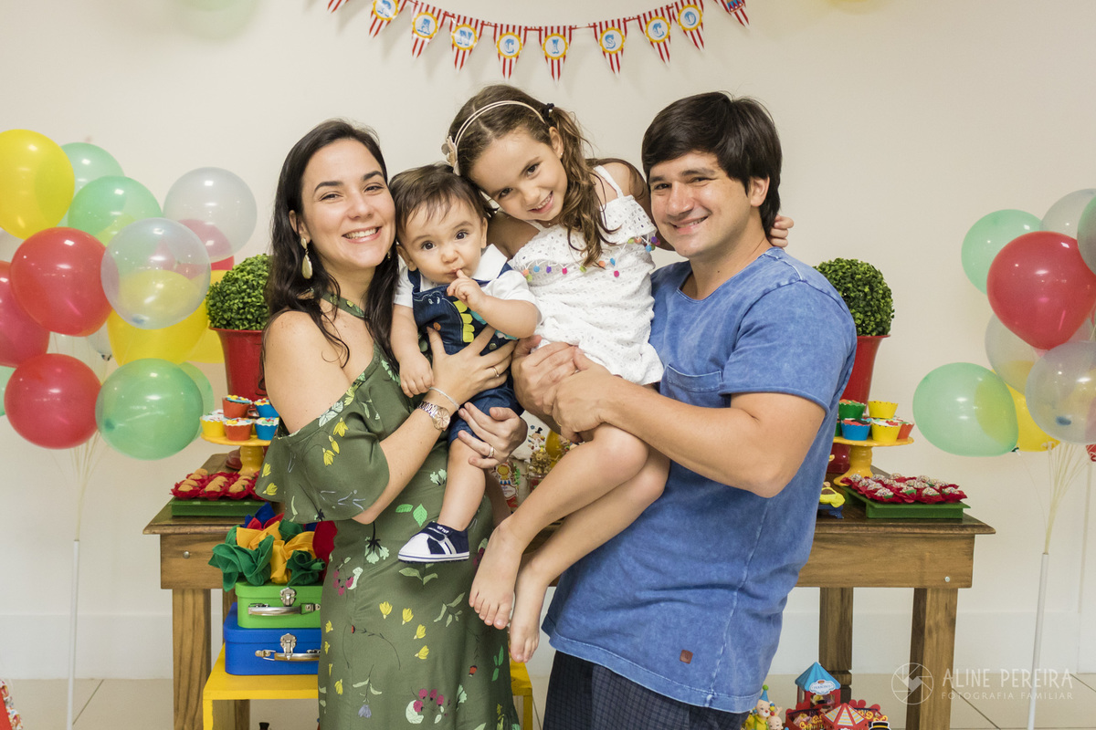 familia abraçada em frente a mesa do bolo decorada com o tema circo