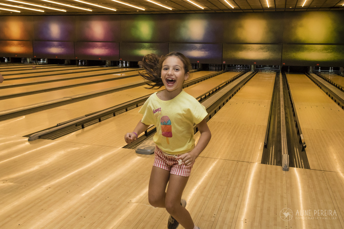 menina feliz depois de fazer um strike no jogo de boliche no Barra Bowling no BarraShopping