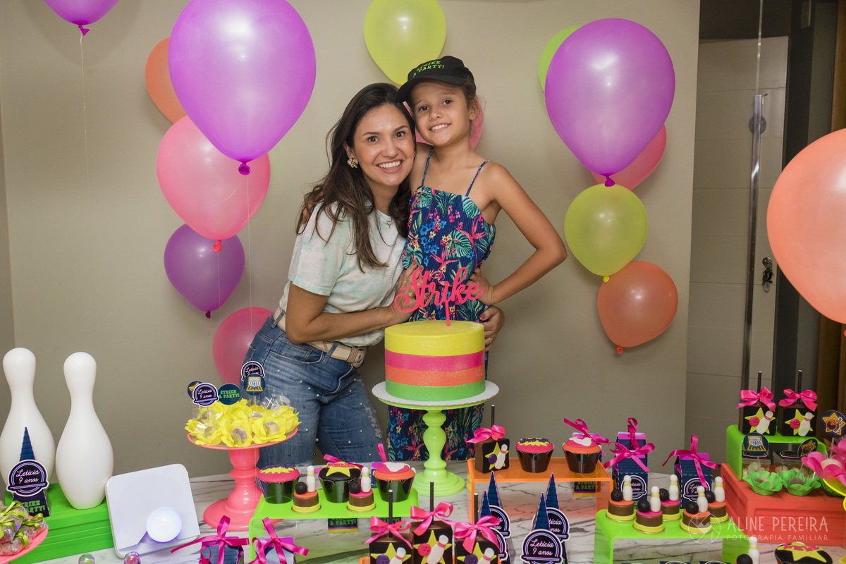 menina com a mãe na mesa do bolo decorada com o tema boliche