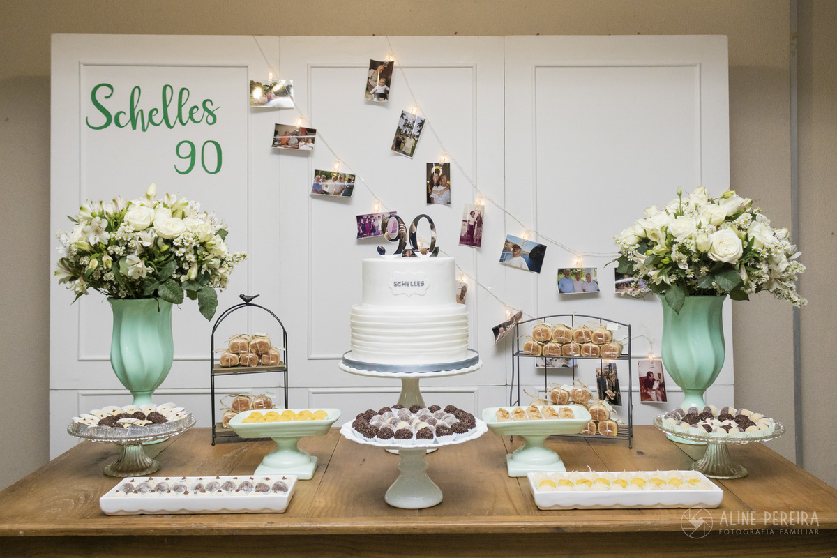 mesa decorada para festa de 90 anos com varal de fotos